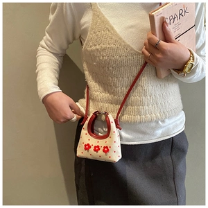Detail van mini beige canvas tas met rode stippen en 3D bloemen aan de schouderband