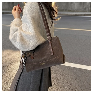Close-up of a vintage brown large capacity tote bag with star charm worn by a model