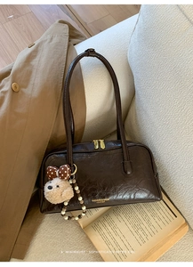 Detail of vintage brown leather underarm bag with cute teddy bear charm and beaded strap