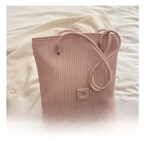 Detail showing the light pink pleated texture and matching square logo on a tote bag