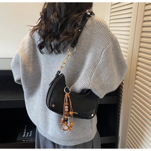 Detail of black leather crescent hobo bag with wood bead tassels and golden chain strap