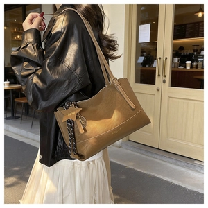 Close-up of retro brown oversized tote bag featuring star charm and metallic pendant