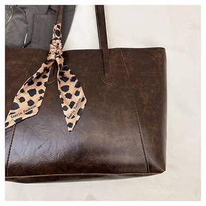 Detail of vintage brown leather tote bag with stylish leopard print silk scarf accessory