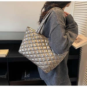 Quilted tote bag in metallic champagne silver finish shown in a lifestyle commuter setting