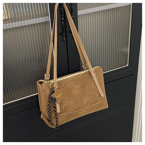 Close-up of a vintage brown faux suede tote bag with star charm and woven rope detail