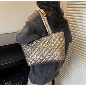 Detail of metallic silver quilted tote bag with diamond pattern and glossy finish
