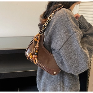 Detailed view of vintage brown saddle bag with gold chain and ethnic bead decoration