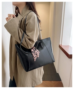 Detail of a black large capacity tote bag with a pink leopard print silk scarf on shoulder