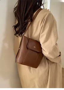 Brown leather bucket bag styled with a beige trench coat for a casual autumn look