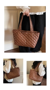 Detail of brown quilted puffer tote bag with glossy finish and wide padded handles