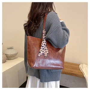 Detail of vintage brown tote bag with leopard silk scarf tied on the handle