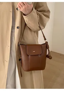 Close-up of brown bucket bag with vertical stitching and knotted decorative ball detail