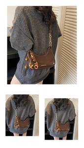 Close-up of brown crescent bag with gold chain strap and vintage wooden bead charm