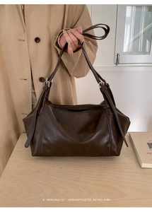 Detail of a dark brown matte leather tote bag with silver buckles and a minimalist design