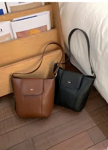 Minimalist leather bucket bags in brown and black with elegant gold buckle detail