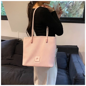 Détail de la texture plissée verticale et du petit logo sur le sac cabas rose clair