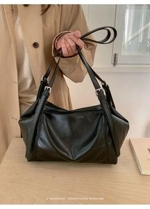 Detail of minimalist black leather tote bag with silver buckles and soft natural texture