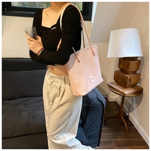 Grand sac cabas plissé rose porté à l'épaule par un mannequin pour un style élégant et chic