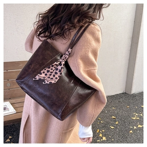 Detail of dark brown tote bag with leopard print scarf on handle in street style setting