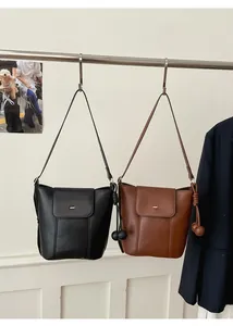 Detail of minimalist leather bucket bags in black and brown with metal buckles