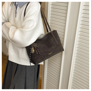 Detail of dark brown tote bag with star charm and metallic tennis racket pendant detail