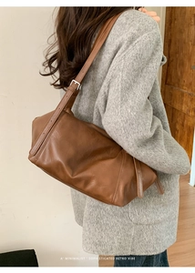 Detail view of a vintage brown leather tote bag showing the adjustable shoulder strap and buckle
