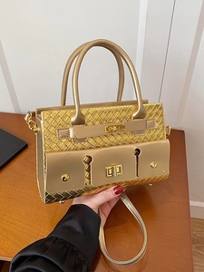 Sac à main en cuir doré tressé avec finition métallique et poignées sur table en bois