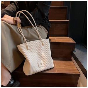 Détail des plis ondulés verticaux sur un grand sac cabas en similicuir crème