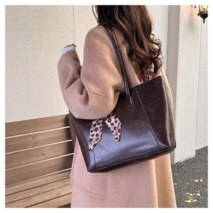 Detail of vintage brown tote bag with decorative leopard print scarf on the shoulder strap