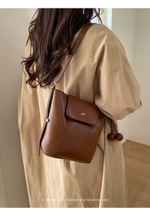 Brown oil wax leather bucket bag worn by model with adjustable crossbody strap