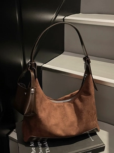 Dark brown suede hobo tote bag with matching mini pouch placed on vintage books