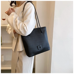 Détail d'un grand sac cabas noir à rayures avec texture plissée porté à l'épaule