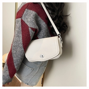 Detail of creamy white litchi grain leather crossbody bag with silver twist lock on model