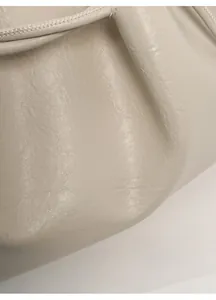 Detail of soft cream leather texture with glossy finish and fine stitching on tote bag