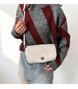Close-up of off-white lychee pattern leather shoulder bag with silver round metal clasp