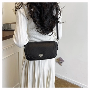 Detail of black pebbled leather shoulder bag with silver turn-lock and adjustable strap
