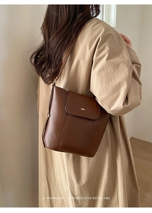 Detail of dark brown leather bucket bag showing refined stitching and metal clasp on flap
