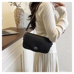 Pebbled leather shoulder bag with silver turn-lock clasp shown on model in home setting