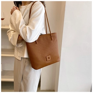 Gros plan du sac cabas en cuir caramel avec texture plissée verticale et fines bandoulières
