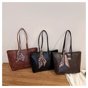 Detailed view of textured leather tote bags with leopard print scarf on handles