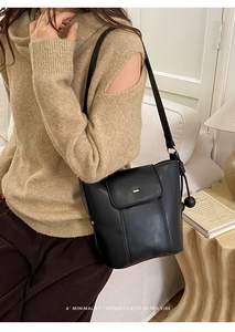 Detail of a black PU leather bucket bag with a metal closure and decorative side knots