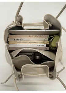 Detail view of large capacity beige tote bag interior holding laptop, books, and umbrella