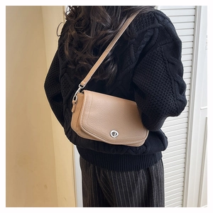 Close-up of khaki lychee grain leather crossbody bag with silver twist lock on a model