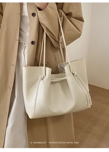 Detailed view of cream-colored tote bag featuring elegant knotted strap accents and soft texture