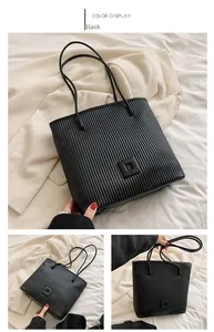Detail view of large black tote bag with vertical pleated texture and square buckle