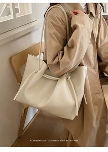 Detail of minimalist cream tote bag showing drawstring knot and lychee grain leather