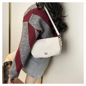 Sac baguette en cuir blanc avec fermoir argenté porté à l'épaule par un mannequin