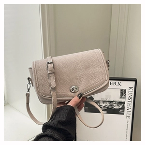 Detail of beige lychee grain leather crossbody bag with silver oval rotating metal lock