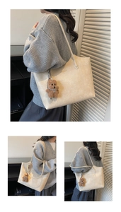 Detail of beige textured leather tote bag with gold logo and plush bear pendant