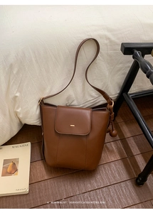 Close-up of retro brown bucket bag featuring woven knot detail and gold metal hardware